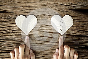Woman hand select between heart and broken heart paper cut on wooden background