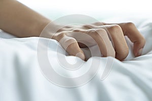 Woman hand with sex orgasm gesture pose acting on white bed, close up