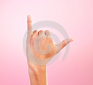 Woman hand, shaka and studio with a icon, emoji and hang ten surfing sign. Isolated, pink background and female hands