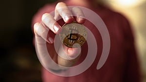 Woman hand showing a bitcoin golden coin to the camera. Bullish BTC, cryptocurrency, 2p2 exchange and blockchain concept