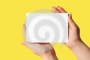 Woman hand showing blank business card on Illuminating Yellow background