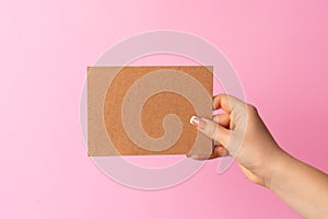 Woman hand showing blank business card on pink background.