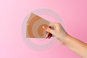 Woman hand showing blank business card on pink background.