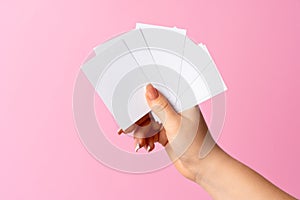 Woman hand showing blank business card on pink background.