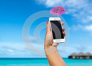 Woman hand showing a blank smart phone on the beach