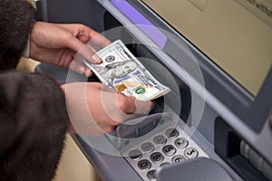 Woman hand showing dollar banknotes in front of the atm