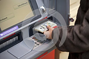 Woman hand showing dollar banknotes in front of the atm