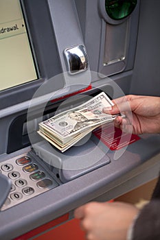 Woman hand showing dollar banknotes in front of the atm