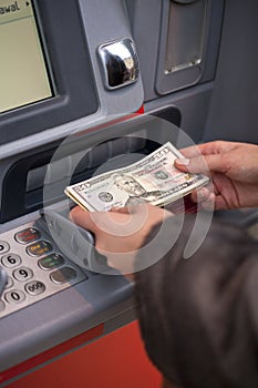 Woman hand showing dollar banknotes in front of the atm