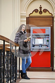 Woman hand showing dollar banknotes in front of the atm