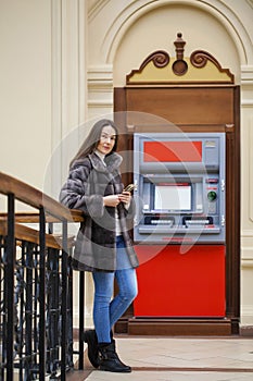 Woman hand showing dollar banknotes in front of the atm