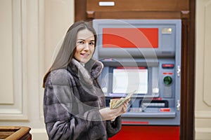 Woman hand showing dollar banknotes in front of the atm