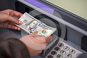 Woman hand showing dollar banknotes in front of the atm