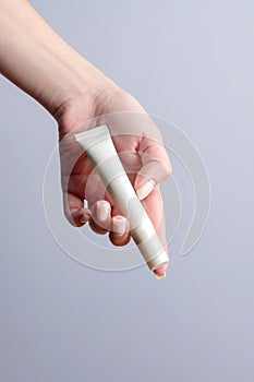 Woman hand showing eye cream product. Cosmetic product branding mockup. Daily skincare and body care routine. Female