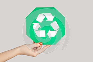 Woman hand showing green recycling sign, environment protection.