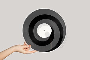 Woman hand showing retro spinning music plate for gramophone.