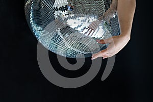 Woman hand on a silver disco ball. Dance club, nightlife, parties. Close-up, black background