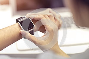 Woman hand with smart watch on wrist, wearable watch and technology computer laptop for communication, checking time