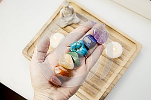 Woman hand sowing all seven color chakra crystal stones.