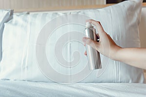 Woman Hand is Spraying Air Freshener into Pillow on Bedroom, Unpleasant Smell and Aromatherapy Concept photo
