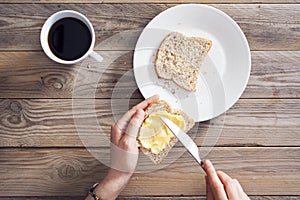 Woman hand spreading butter on sliced bread