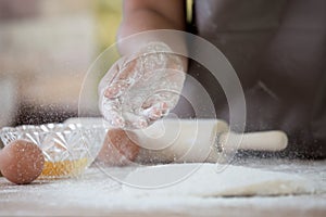 Woman hand sprinkling white flour on dough