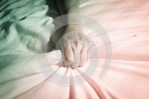 Woman hand squeezing blanket on bed