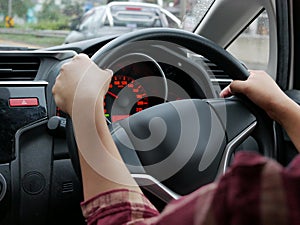 Woman hand on steering wheel driving a car with both hands