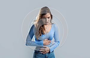 Woman with hand on stomach because nausea, painful disease feeling unwell. Ache concept. Stomach pain and others stomach