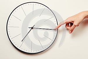 Woman hand stop time on a round clock, time management and deadline concept