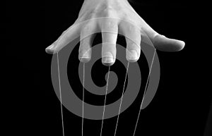 Woman hand with strings on fingers. Influence, manipulation, abuse, domination concept. Black and white.