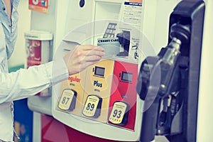 Woman hand swiping credit card at gas pump station photo