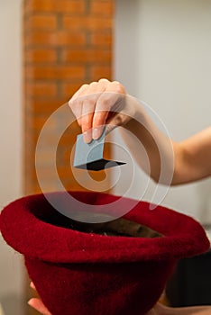 Woman hand take a card with a name from hat