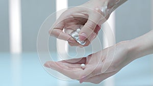 Woman hand take pills from blister pack. Medicament dose pill in hand