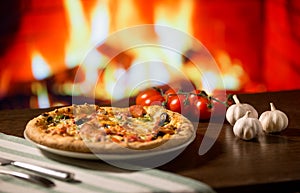 Woman hand take slice of Pizza over fireplace background with tomatoes