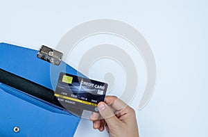 Woman hand taking out the credit card from blue purse for payment on the white background. Finance and money concept, top view,