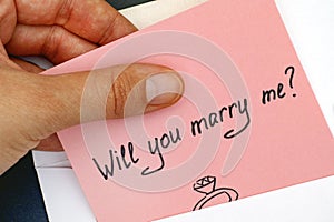 Woman hand taking out letter with text Will you marry me? from e