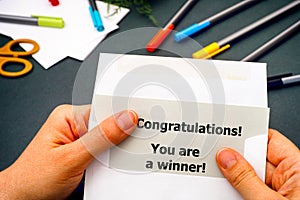 Woman hand taking out letter with words Congratulations! You are a winner! from envelope
