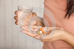 Woman hand taking pill and glass of water in hand