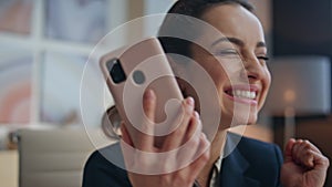 Woman hand taking smartphone rejoicing success in office closeup. Excited girl