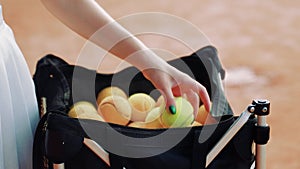 Woman hand taking tennis balls out of a bag on a court