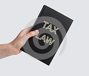 Woman hand with tax law book. Revenue legislation, study of rules to assess and collect levies concept. Code, legal