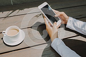 Woman hand texting for someone with black screen at coffee shop