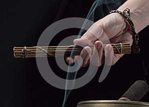 Woman hand with tibetan singing bowl and incense sticks