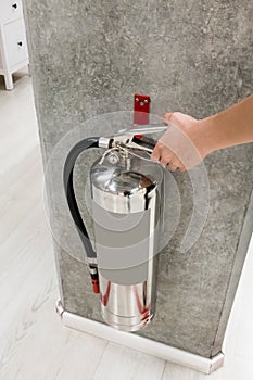 Woman hand touching and checking the chrome fire extinguisher