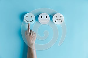 Woman hand touching happy face smile face icon on round blue object. Customer experience and service with satisfaction concept.