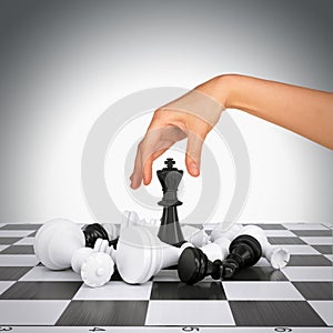 Woman hand touching king figure on chess board