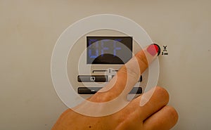 Woman hand try to turn off and on the central heating in the room. Female hands on the central heating control panel. Girl hand