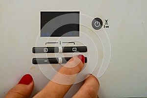 Woman hand try to turn off and on the central heating in the room. Female hands on the central heating control panel. Girl hand