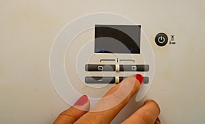 Woman hand try to turn off and on the central heating in the room. Female hands on the central heating control panel. Girl hand